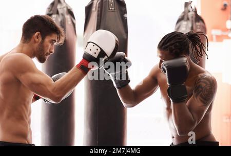 Adversaires et amis de boxe. un jeune boxeur pratiquant sa perforation avec un partenaire. Banque D'Images