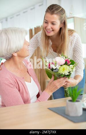 une belle mère pleine de joie d'âge moyen tient un cadeau de fleur Banque D'Images