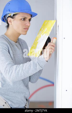 femme travaillant plâtrage les murs à l'intérieur de la maison Banque D'Images