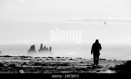 Une belle vue d'un homme marchant sur la plage avec des falaises autour Banque D'Images