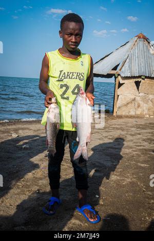 Un pêcheur de la tribu El Molo tenant un poisson à El Molo Vilage dans le lac Turkana, Kenya Banque D'Images