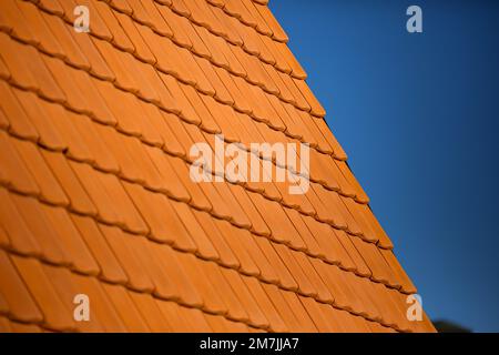 Détails des motifs de toit en tuiles de brique orange avec ciel bleu clair en arrière-plan. Gros plan sur les modèles d'architecture de la maison. Banque D'Images