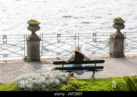 Une femme touristique assise sur un banc dans le jardin de la Villa Monastero en regardant le lac de Côme, en Italie Banque D'Images