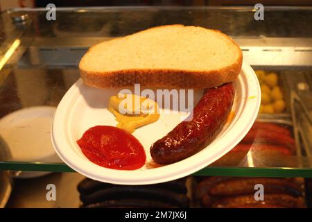 Saucisse, tranche de pain, sauce tomate, moutarde sur une assiette en plastique Banque D'Images