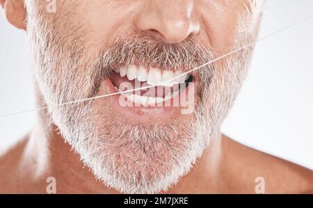 Fil dentaire et visage de l'homme âgé en studio isolé sur fond gris. Nettoyage, hygiène et modèle mâle âgé avec produit dents en soie dentaire pour Banque D'Images