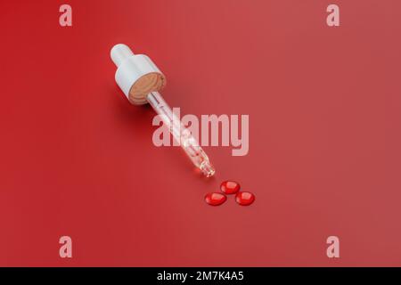 Maquette de bouchon de flacon en verre compte-gouttes. Pipette cosmétique. arrière-plan rouge. Concept de cosmétiques anti-âge et de beauté. minimalisme, soins de la peau Banque D'Images