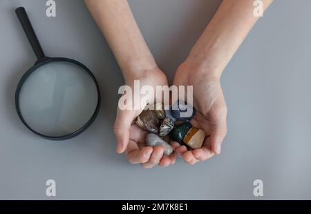 collection de plusieurs pierres semi-précieuses pour les enfants dans les mains sur un bureau gris Banque D'Images