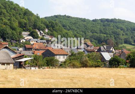 Moulis Village toits rouges avec un champ de paille au premier plan et les montagnes des Pyrénées au fond. Banque D'Images