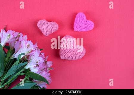 Composition de fleurs violettes Alstroemeria avec un coeur tricoté rose sur fond rose. Concept de la Saint-Valentin, salutations pour un être cher, top vi Banque D'Images