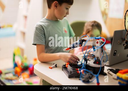 Les enfants apprennent à réparer le bras robot de commande de leçon, le bras de machine robotique dans l'atelier à domicile, la technologie future éducation scientifique. Banque D'Images