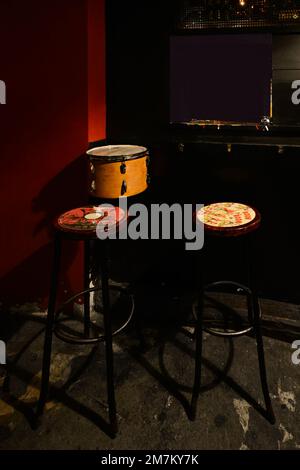 Coin d'une salle de musique avec un tambour et une paire de grands tabourets en bois et en métal Banque D'Images