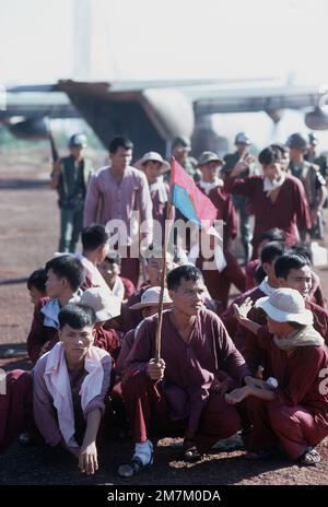 Les prisonniers de guerre du Viet Cong, dont l'un porte-drapeau est le Viet Cong, se tiennent et s'assoient au lieu de l'échange. Ils ont été transportés à bord d'un avion C-130 de l'USAF à partir de la base aérienne de Bien Hoa. Ils seront échangés contre des prisonniers de guerre américains et sud-vietnamiens détenus par les forces du Viet Cong. Sujet opération/série: HOMECOMING base: LOC Ninh pays: Vietnam du Sud Banque D'Images