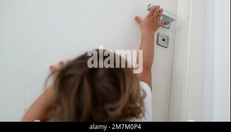 Bébé essayant d'atteindre le bouton de la porte. Enfant sur la pointe des orteils atteignant pendant door2 Banque D'Images