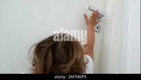 Bébé essayant d'atteindre le bouton de la porte. Enfant sur la pointe des orteils atteignant pendant door2 Banque D'Images