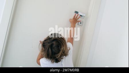 Bébé essayant d'atteindre le bouton de la porte. Enfant sur les orteils de pointe atteignant pour la porte Banque D'Images