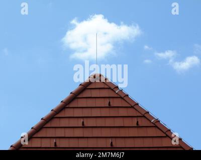 toit incliné en argile brune. brise-neige en métal. carreaux de faîte et hanche. barre d'éclair en acier. matériaux de construction de toit. ciel bleu avec nuages Banque D'Images