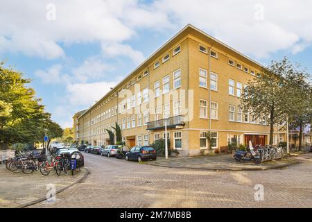 un grand bâtiment avec beaucoup de vélos garés à l'avant et sur la rue à côté est un ciel bleu rempli de nuages blancs Banque D'Images