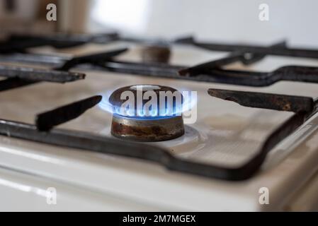 La flamme d'un vieux poêle à gaz brûle dans une cuisine. Banque D'Images