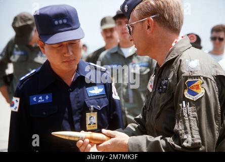 Un membre de l'équipage d'un Avion A-10 Thunderbolt II présente une carapace de canon factice du canon General Electric GAU-8/A Avenger 30mm sur l'A-10 au commandant d'une base aérienne en Corée. Une carapace a été présentée au commandant de chaque base visité par l'équipage A-10 au cours de la visite afin de familiariser les commandants de terrain avec les capacités de l'avion. Pays: Corée du Sud Banque D'Images