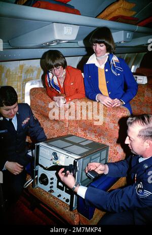 Le sergent technique Joseph J. Ostrowski (1), un technicien de mesure de précision avec la section précise du temps au Centre de métrologie et d'orientation aérospatiales de la station de l'Armée de l'air de Newark, Ohio, aide à fixer une horloge « atomique » à faisceau de césium au siège d'un avion de ligne commercial. L'horloge est utilisée pour synchroniser les horloges de la Force aérienne critique. Pays : inconnu Banque D'Images