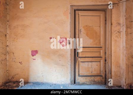 Italie, Vénétie, salle poussiéreuse d'une maison abandonnée, porte fermée et murs rose saumon Banque D'Images