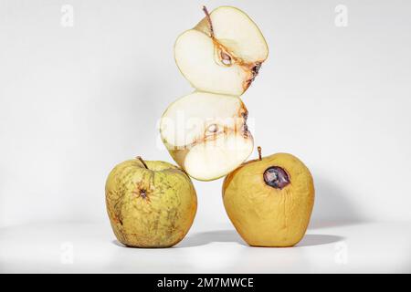 Pommes pourries, déshydratées et pourries, une pomme coupée en deux, deux moitiés de pomme, fruits isolés sur fond blanc Banque D'Images