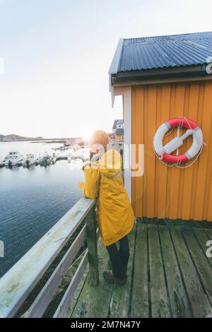 Jeune femme avec imperméable jaune en Norvège, Lofoten, village de pêcheurs Banque D'Images