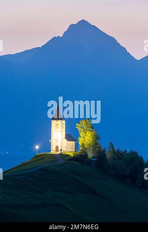 L'église emblématique de Jamik, avec le Mont Triglav en arrière-plan, illuminée avant le lever du soleil. Jamnik, Kranj, haute-Carniola, Slovénie. Banque D'Images
