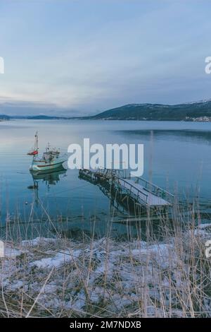 Vieux bateau de pêche sur la jetée en Norvège, paysage de neige et de glace en Scandinavie, région côtière, bateau, mer, fjord Banque D'Images