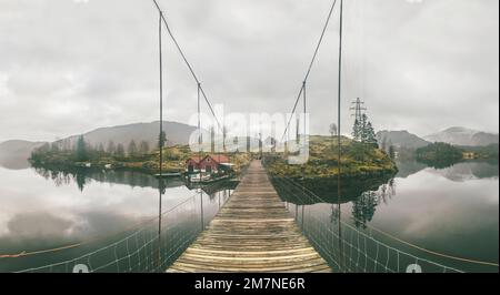 Vieux pont suspendu en bois dans le fjord, groupes d'îles avec cabanes de pêche, maisons, bateaux, poteaux électriques en Norvège, paysage avec village de pêche solitaire, paysage typique du fjord avec de petites îles, Scandinavie Banque D'Images