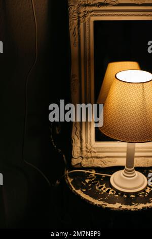 Petite lampe de table éclairée devant le miroir ancien Banque D'Images