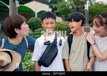 Quatre Japonais sur une sortie, deux femmes matures et deux garçons de 13 ans, dans une rangée, riant. Banque D'Images