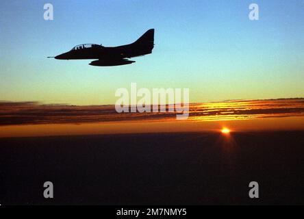 Une vue latérale gauche silhouetée d'un avion Skyhawk TA-4J de l'escadron composite des douze (VC-12) en vol avec un soleil couchant en arrière-plan. VC-12 est basé à la base aérienne navale Oceana, en Virginie. Date exacte prise de vue inconnue. Pays: Océan Atlantique (AOC) Banque D'Images