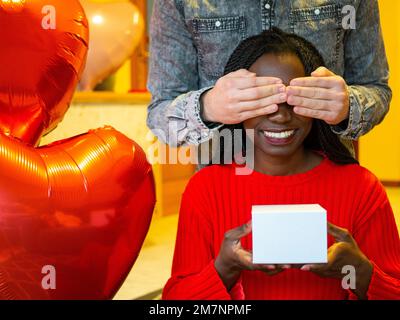 Portrait d'un couple interracial avec une boîte blanche couvrant ses yeux pendant la Saint Valentin Banque D'Images