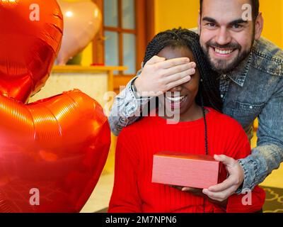 Portrait d'un couple interracial avec une boîte blanche couvrant ses yeux pendant la Saint Valentin Banque D'Images