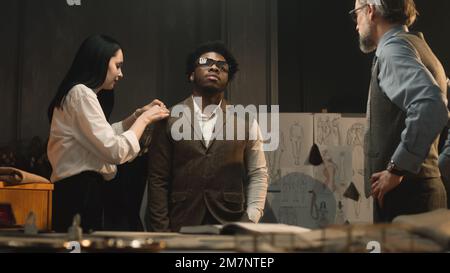 Manches de tailleur pour femme, à discuter avec la taille du client et le tissu. Un homme d'affaires afro-américain porte une veste de mariage et parle avec un designer masculin. Mode concept. Banque D'Images