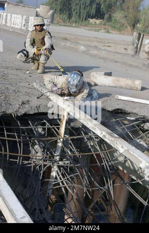 041116-M-1250B-012. [Complet] Légende de la scène: US Navy (USN) Seabee, PETIT officier 1st classe (PO1) Hector Calderon (arrière), détachement de Kalsu (DET), Bataillon de construction mobile navale 4 (NMCB-4), 24th Marine Expeditionary Unit (MEU), tient une sangle attachée au harnais porté par USN Seabee, petit officier 2nd classe (PO2), NMCB-4, Jim Musksch, Nevsu, Kusch, MAB. 24th MEU, afin de sécuriser PO2 Muskevitsch en soudant une poutre de soutien dans un cratère d'impact de mortier alors qu'ils travaillent sur un pont qu'ils sont en train de reconstruire à Mahmuydiyah (province de Babil), en Irak, qui a été gravement endommagé par des attaques répétées b Banque D'Images