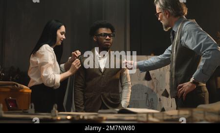 Manches de tailleur pour femme, à discuter avec la taille du client et le tissu. Un homme d'affaires afro-américain porte une veste de mariage et parle avec un designer masculin. Mode concept. Banque D'Images