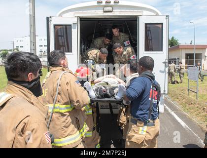 Les membres du Service des incendies du Groupe médical 374th et du Squadron du Génie civil 374th se préparent à transporter une personne simulée blessée au cours d'un exercice d'intervention en cas d'accident majeur à la base aérienne de Yokota, au Japon, au 11 mai 2022. Le MARE a testé la réponse de la base à une simulation d’écrasement du Faucon Fighting Faucon F-16 et la capacité de collaborer avec les partenaires de la mission. Grâce au soutien de l'installation aérienne navale Atsugi, commandant des activités de la flotte Yokosuka, de la base aérienne de Misawa et du service des incendies de Tokyo, de la station incendie de Fussa, c'était la plus grande MARE de l'histoire de Yokota. Banque D'Images