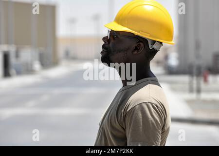 Le principal Airman Dennis Nyenje, spécialiste de la structure du magasin de structures de l'escadron expéditionnaire du génie civil de 380th, sert de guide au sol pour les aviateurs qui exploitent un pont élévateur 11 mai 2022 à la base aérienne d'Al Dhafra, aux Émirats arabes Unis. Les spécialistes des structures, ou « 3ans3 », sont responsables de la construction de structures depuis le sol et sont chargés de réparer ces structures, parfois dans des environnements dangereux ou de combat. Banque D'Images