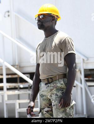 Le principal Airman Dennis Nyenje, spécialiste de la structure du magasin de structures de l'escadron expéditionnaire du génie civil de 380th, sert de guide au sol pour les aviateurs qui exploitent un pont élévateur 11 mai 2022 à la base aérienne d'Al Dhafra, aux Émirats arabes Unis. Les spécialistes des structures, ou « 3ans3 », sont responsables de la construction de structures depuis le sol et sont chargés de réparer ces structures, parfois dans des environnements dangereux ou de combat. Banque D'Images