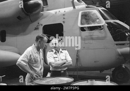 LE CAPT John R. Batzler, commandant du porte-avions à propulsion nucléaire USS NIMITZ (CVN-68), à gauche, et col Keating (États-Unis) Air Force, discuter des plans finaux de l'opération Evening Light, une mission de sauvetage en Iran. Ils sont debout devant un hélicoptère de Stalion de mer RH-53 stationné dans la baie hangar à bord du NIMITZ. Objet opération/série : LUMIÈRE DU SOIR pays : Océan Indien (CIO) Banque D'Images