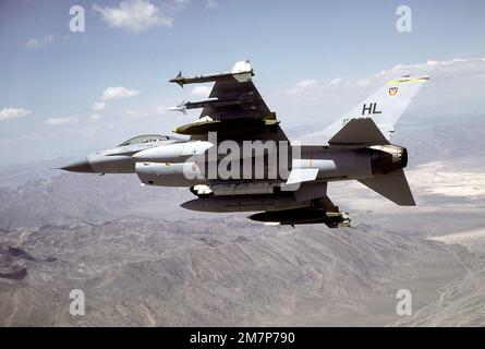 Vue arrière du dessous gauche d'un F-16 Fighting Falcon se trouvant à droite au-dessus de la base aérienne de Nellis. Un AIM-9L Sidewinder, un AIM-9J Sidewinder, un 2 000 lb. La bombe Mark 84 et un réservoir de carburant auxiliaire se trouvent sur chaque aile. UN module de contre-mesures électronique ALQ-119 est monté sur la ligne centrale. L'aéronef est affecté au 4th Escadron d'appui tactique, 388th Escadre d'appui tactique. État: Nevada (NV) pays: Etats-Unis d'Amérique (USA) Banque D'Images