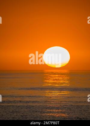 Soleil sur le point de se coucher dans un ciel orange vide juste au-dessus de l'horizon au-dessus du golfe du Mexique Banque D'Images