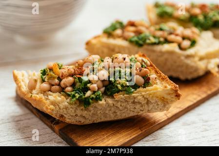 Pesto de kale vegan maison avec bruschetta de haricots blancs sur une planche à découper. Banque D'Images