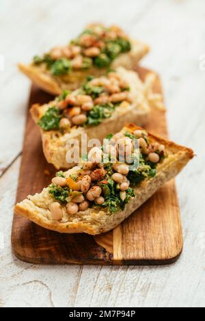 Pesto de kale vegan maison avec bruschetta de haricots blancs sur une planche à découper. Banque D'Images