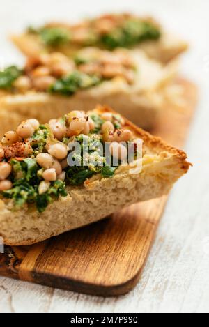 Pesto de kale vegan maison avec bruschetta de haricots blancs sur une planche à découper. Banque D'Images