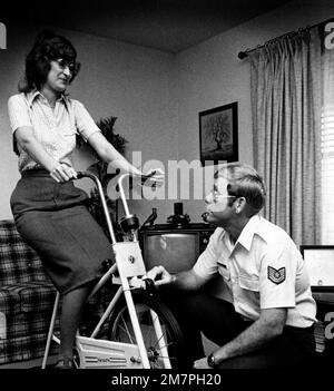 TSGT Bob King ajuste la tension sur le vélo d'exercice sa femme est pédalier. Katy King serait probablement morte aujourd'hui si elle n'avait pas eu de greffe cardiaque sur 4 avril 1975. Base: Fort Sam Houston, San Antonio État: Texas (TX) pays: États-Unis d'Amérique (USA) Banque D'Images