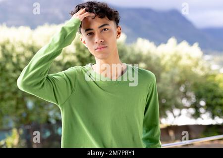 Image de l'homme biracial en vert haut à manches longues avec espace d'imitation sur les arbres en arrière-plan Banque D'Images