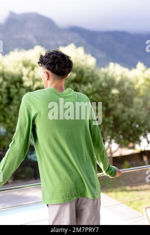 Image de l'homme biracial en vert haut à manches longues avec espace d'imitation sur les arbres en arrière-plan Banque D'Images